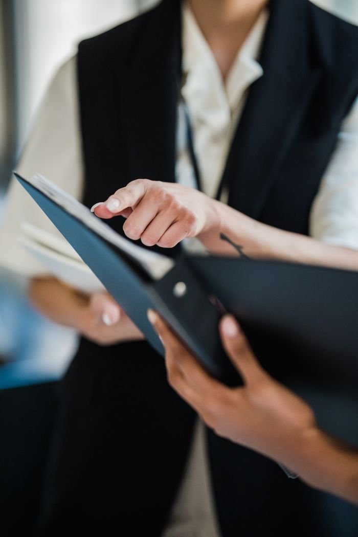 Two professionals pointing at documents during a collaborative office meeting.