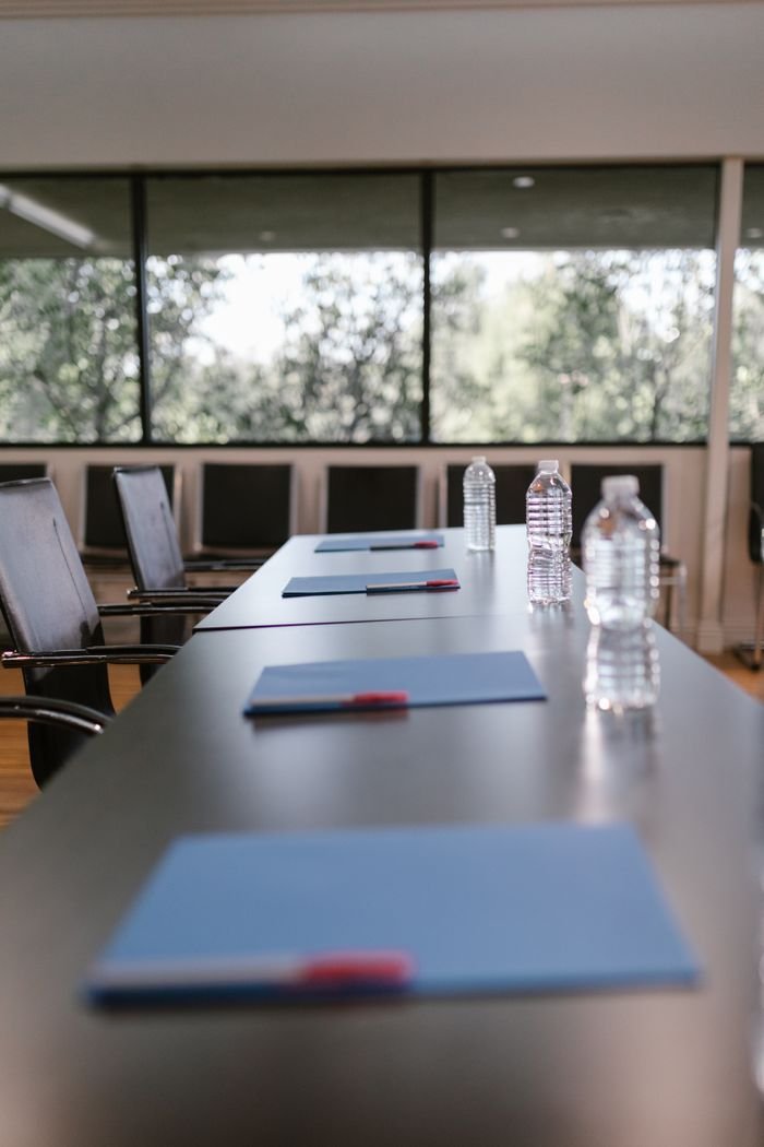 A modern conference room setup with chairs, water bottles, and notebooks on a wooden table.