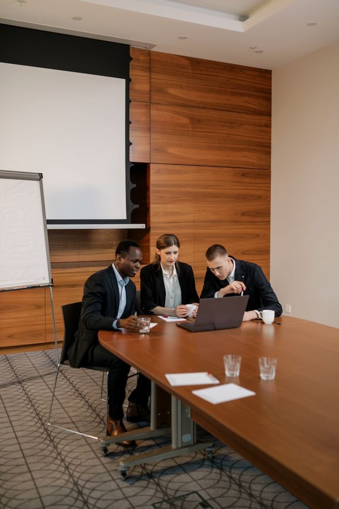 Diverse team engaged in a business meeting, discussing plans and strategies using a laptop.